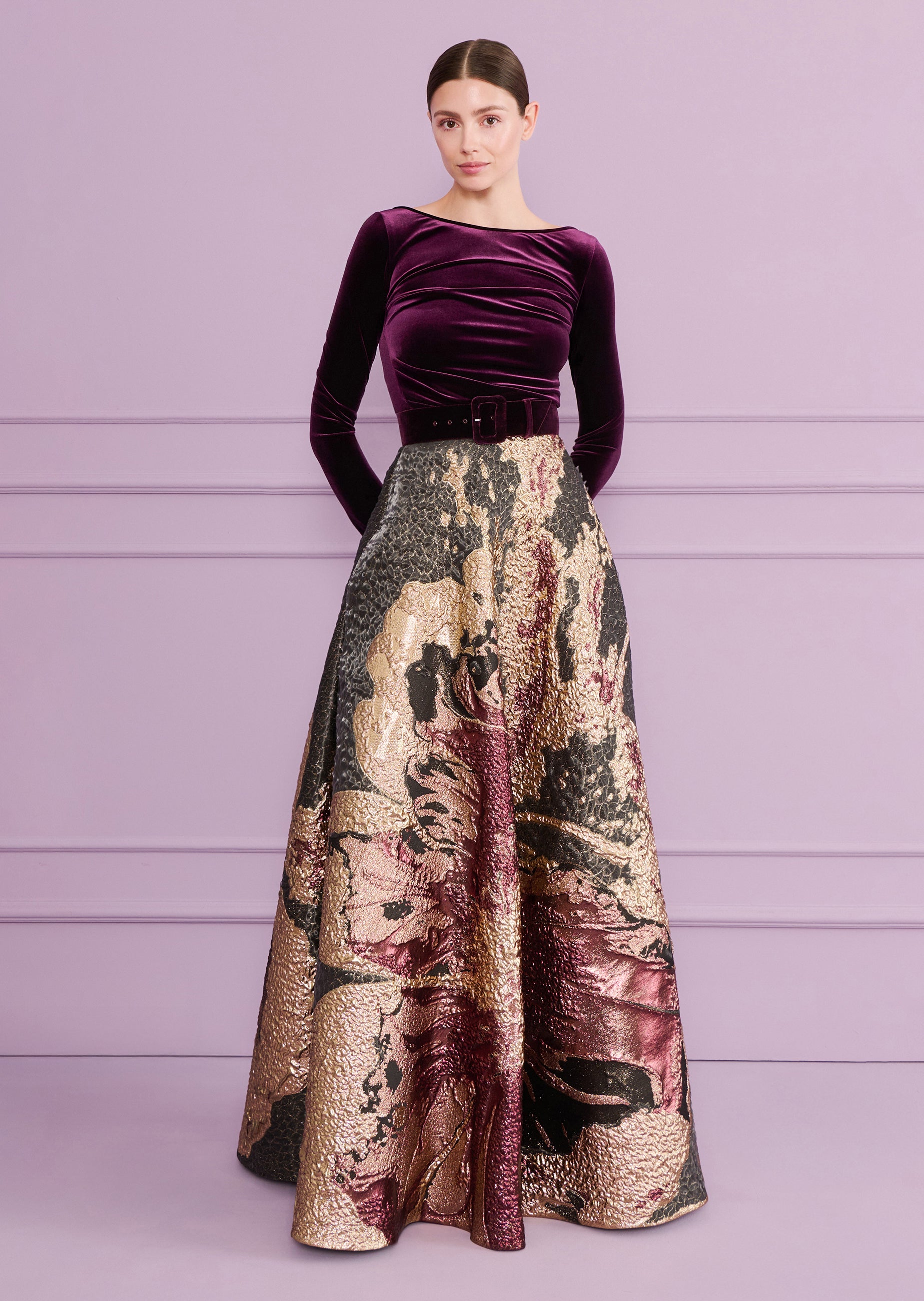 Aubergine velvet gown with ruched boat-neck top, matching belt, and a gold-toned, black, aubergine textured skirt.