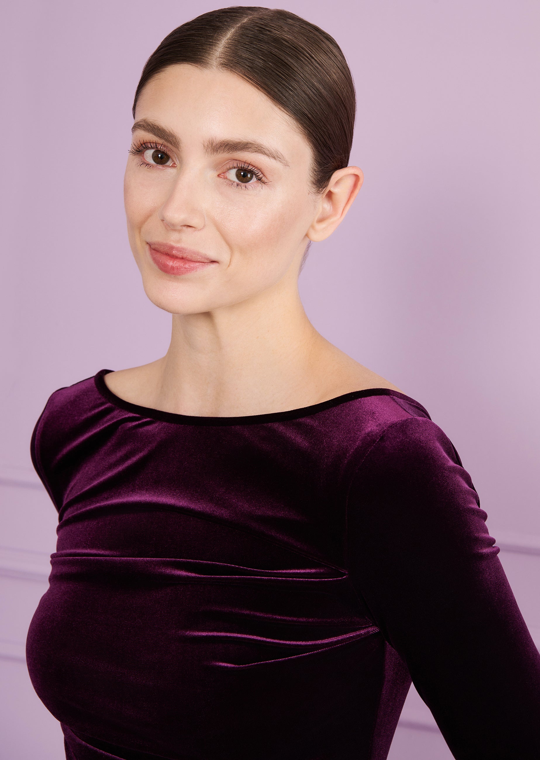 Aubergine velvet long-sleeve top with a boat neck, black trim, and gathered details.