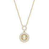 A macro studio photograph focusing on the detailed front composition of the Escada Clara necklace pendant, highlighting the small upper pearl loop, the central golden EE logo with a crystal border, and the outer pearl trim.