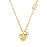 A direct macro shot focusing on the details of the Escada Mina necklace, highlighting the concentric layered heart pendant, the brilliant bezel crystal charm, and the crystal-paved inline monogram station.