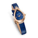 Three-quarter studio perspective highlighting the elegant curve of the warm rose gold pear-shaped case, the polished finish, and the natural grain lines on the inside of the blue leather strap.
