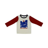 A two-piece Petit Bateau pajama set with a white long-sleeved top featuring red raglan sleeves and a large blue graphic print with a sailboat, paired with solid navy blue trousers.