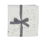 A white square cotton terry baby towel from Petit Bateau featuring a corner hood with a multicolored floral print and a small logo.