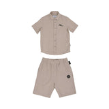 Front view of a beige Philipp Plein Junior shirt and shorts set made from linen, featuring black script branding and a logo patch.