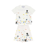 Front view of a white Philipp Plein Junior t-shirt and shorts set featuring a multi-color paint splatter design and black logo branding.