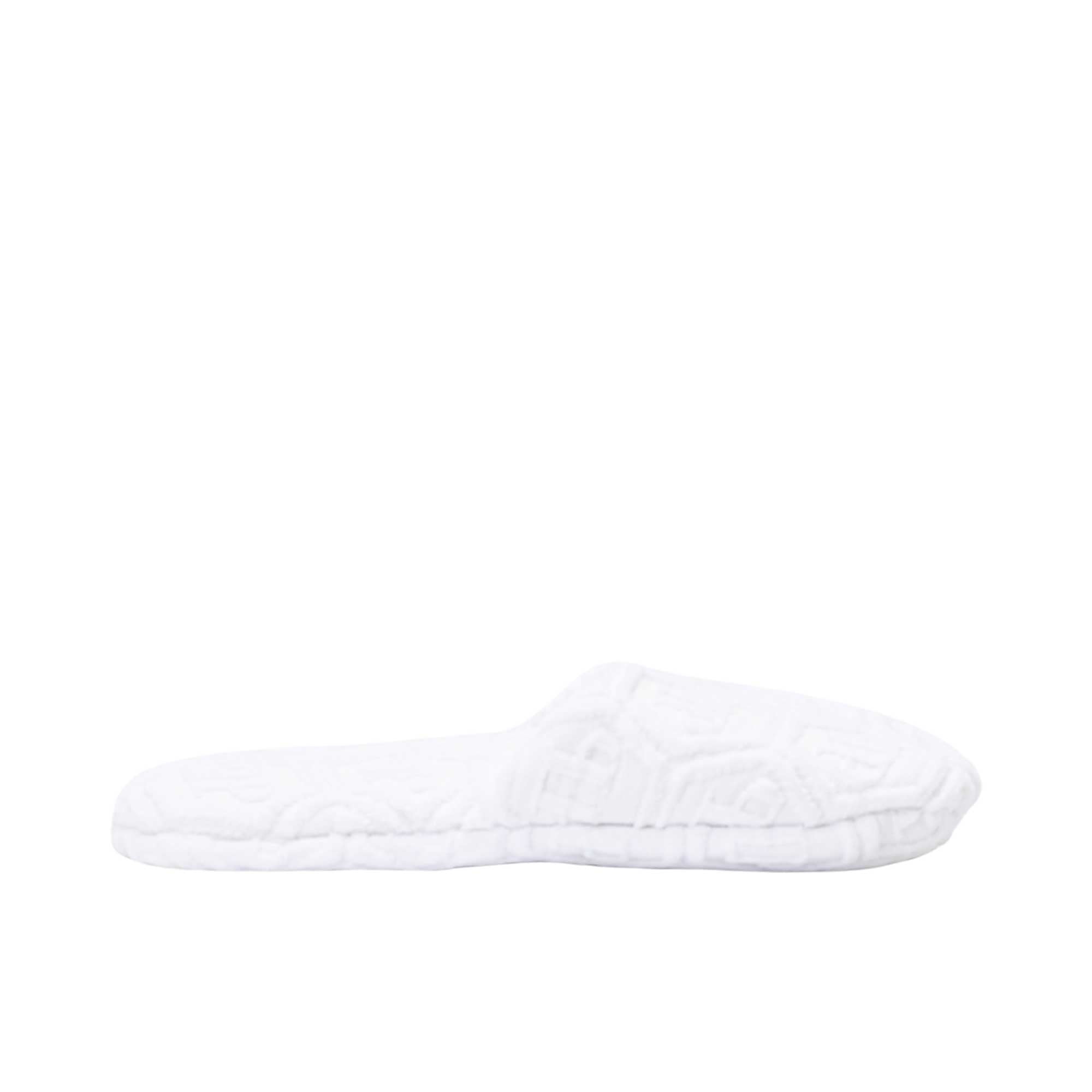 A white terry cotton slipper is shown in a side profile view, highlighting the open-back and the hexagonal logo pattern on the fabric.