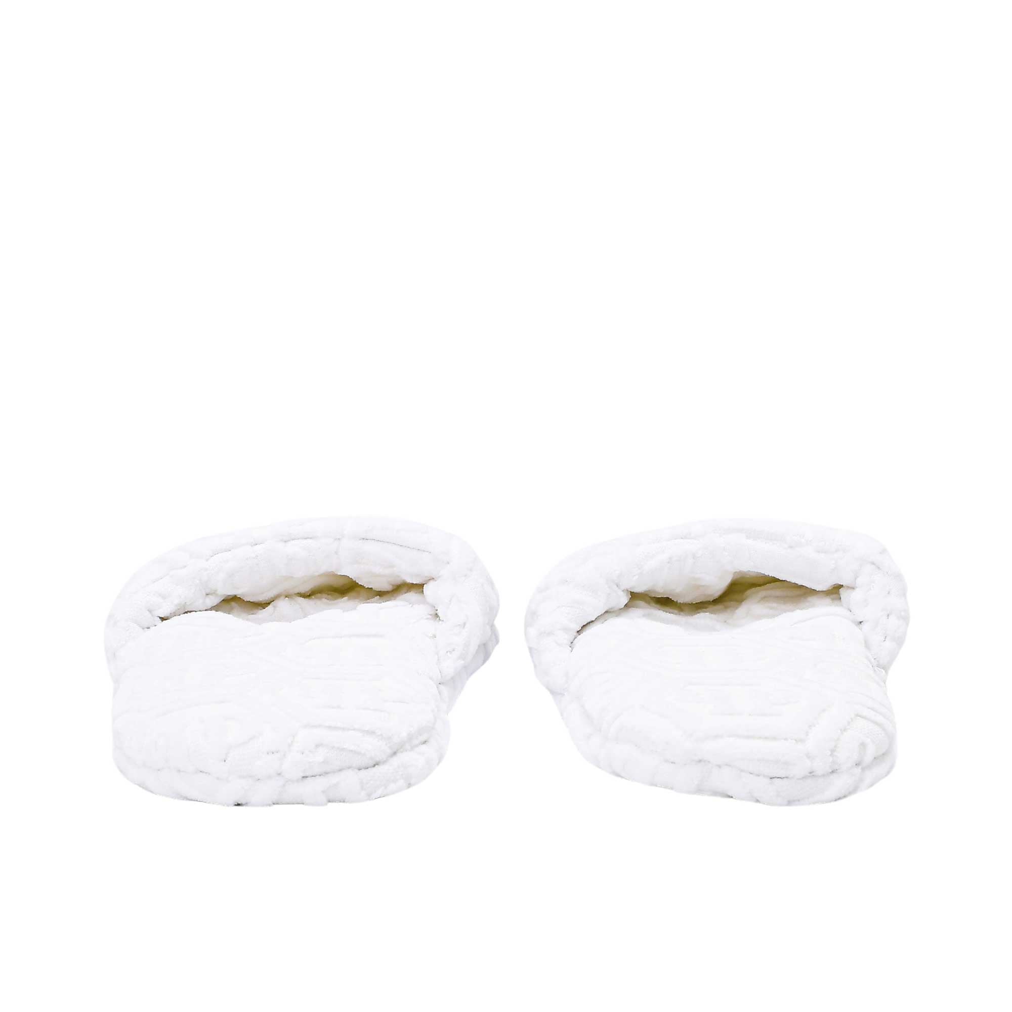 The open toe openings of a pair of white terry slippers, revealing the padded interior and the repeating logo design.
