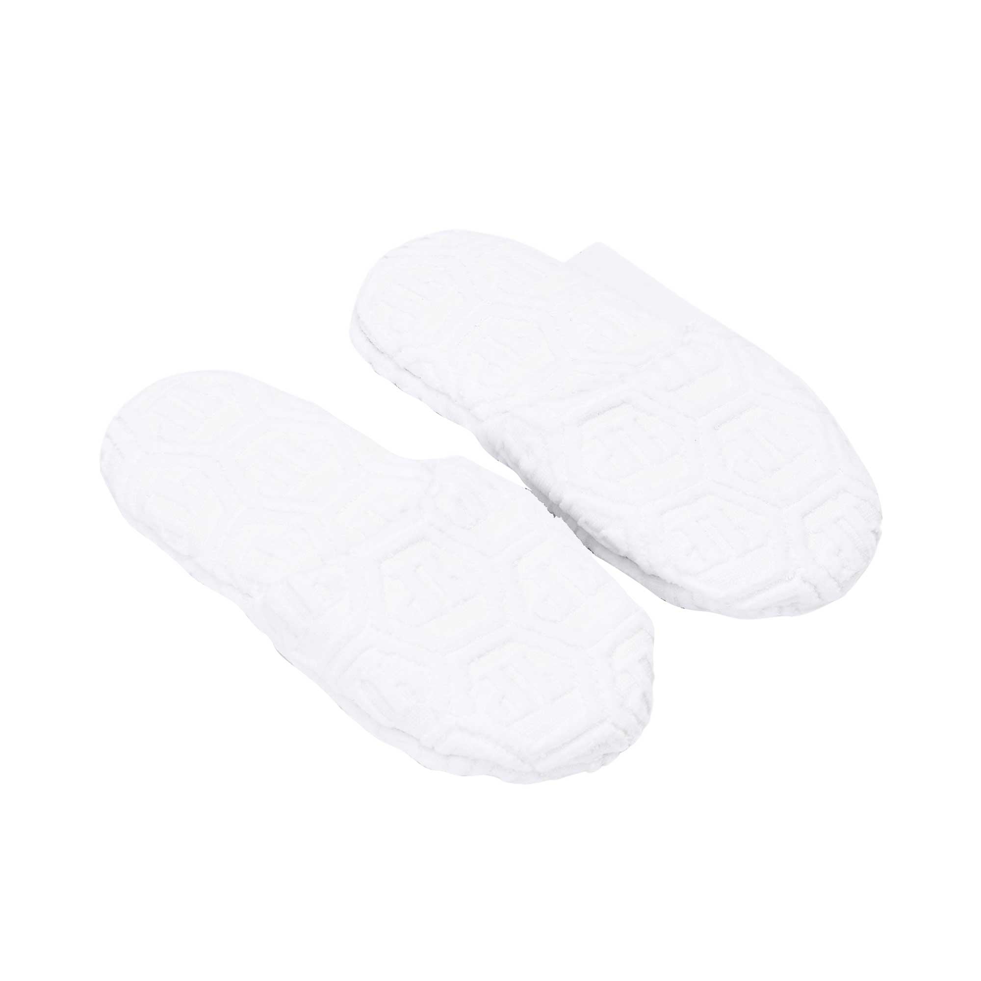 A three-quarter perspective shot from above showing a pair of white terry slippers, capturing both the design of the insole and the texture.