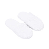 A three-quarter perspective shot from above showing a pair of white terry slippers, capturing both the design of the insole and the texture.