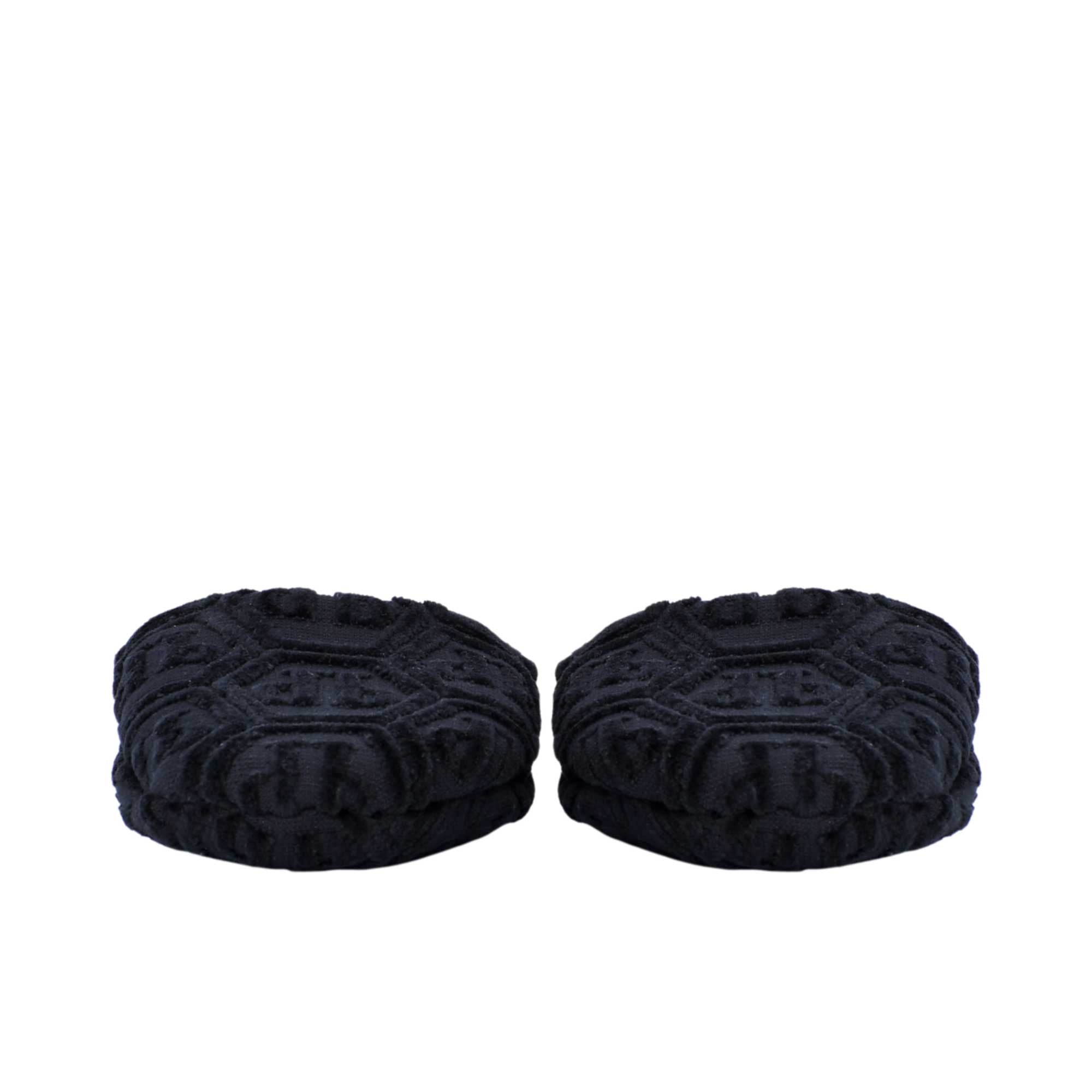 A close-up view focusing on the padded front parts of a pair of black terry slippers, clearly showing the intricate hexagonal PP logo pattern.