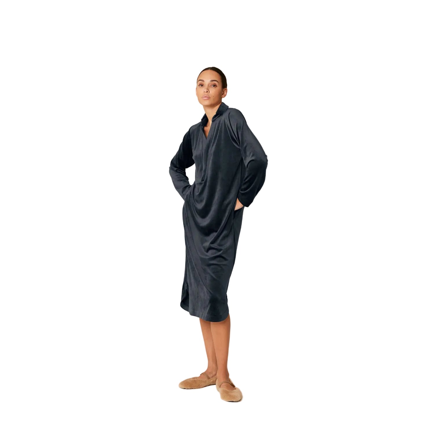 A model wearing a long-sleeve dark blue velvet midi lounge dress by Pluto, featuring a V-neckline with a collar, side pockets, and a relaxed, draped silhouette.