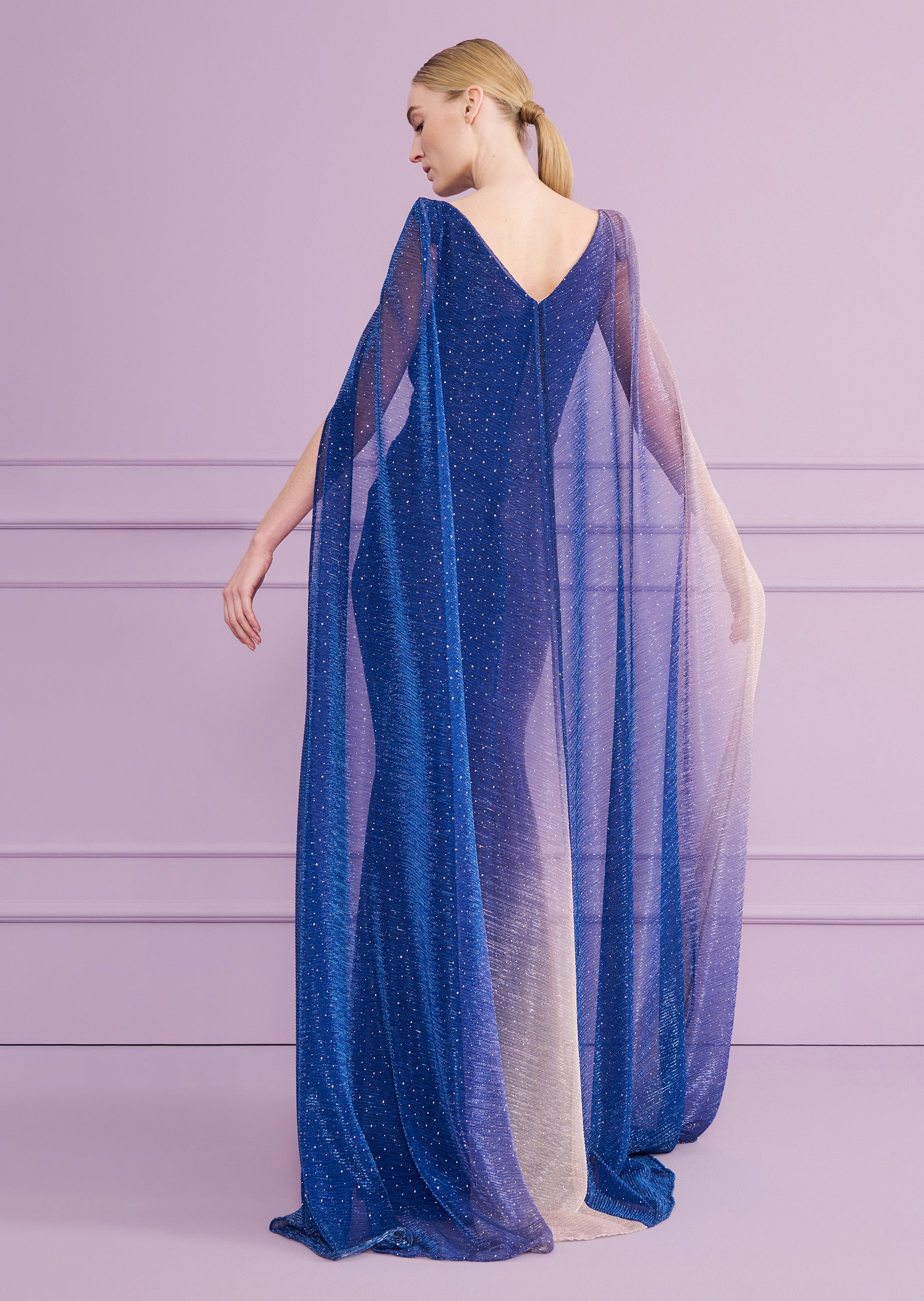 Cornflower blue long dress with a V-neck back and a sheer, shimmery cape overlay that fades from blue to gold-toned.