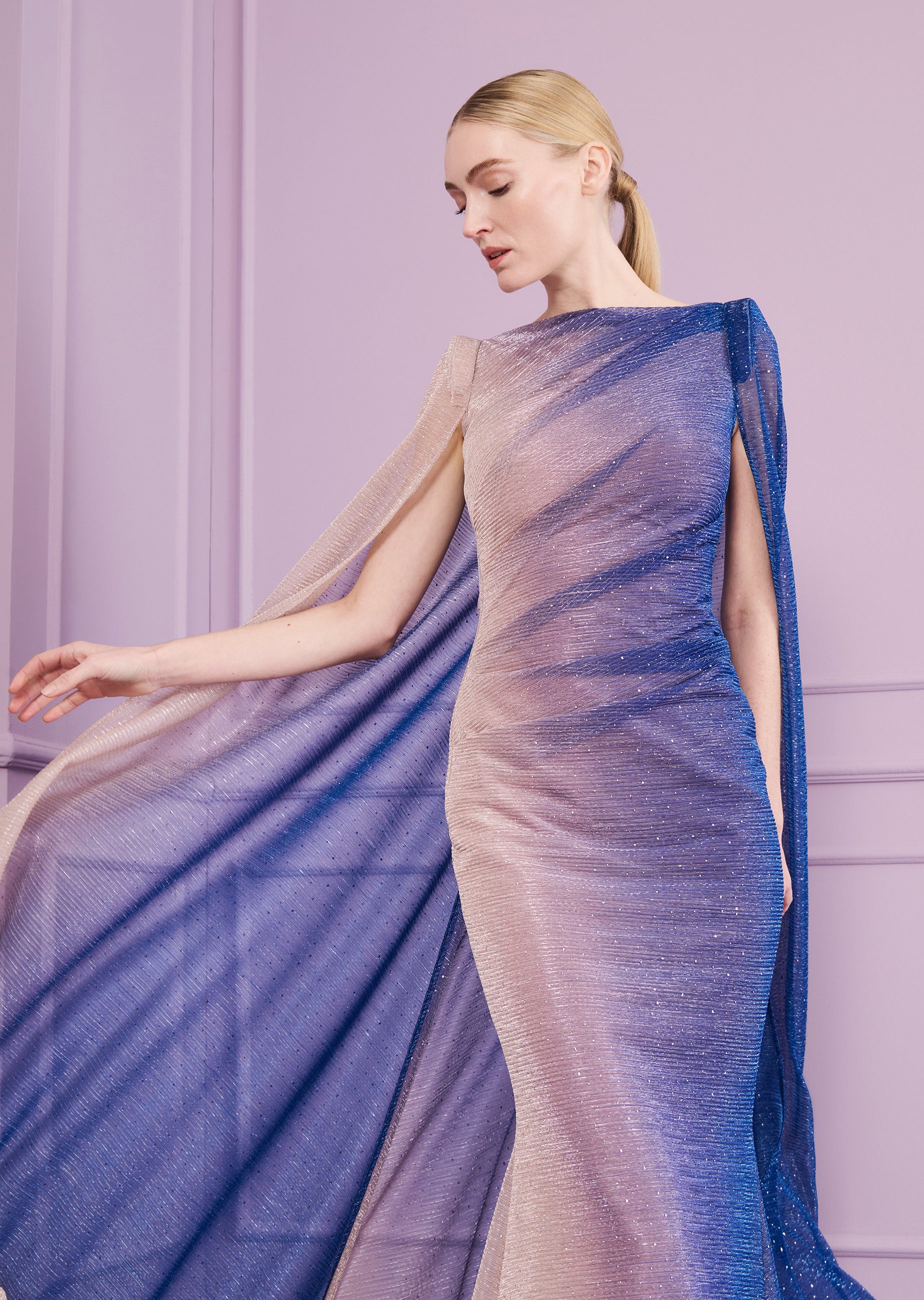 Glittery ombre long dress, beige to cornflower blue, with pleated texture, boat neck, and flowing cape sleeves.