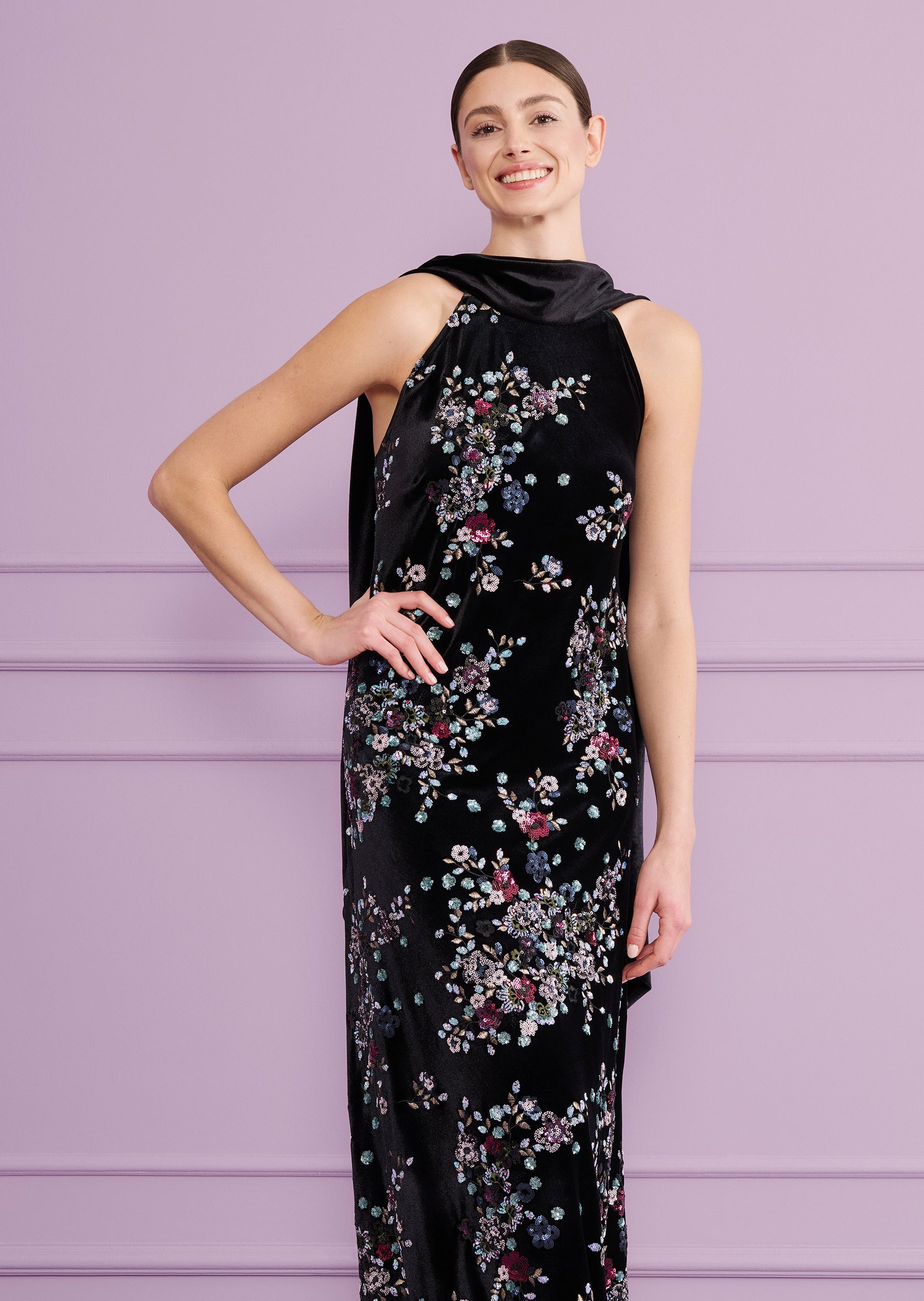 Black velvet long dress with a halter neck and draped scarf detail. Features scattered floral embroidery and sequins in vario