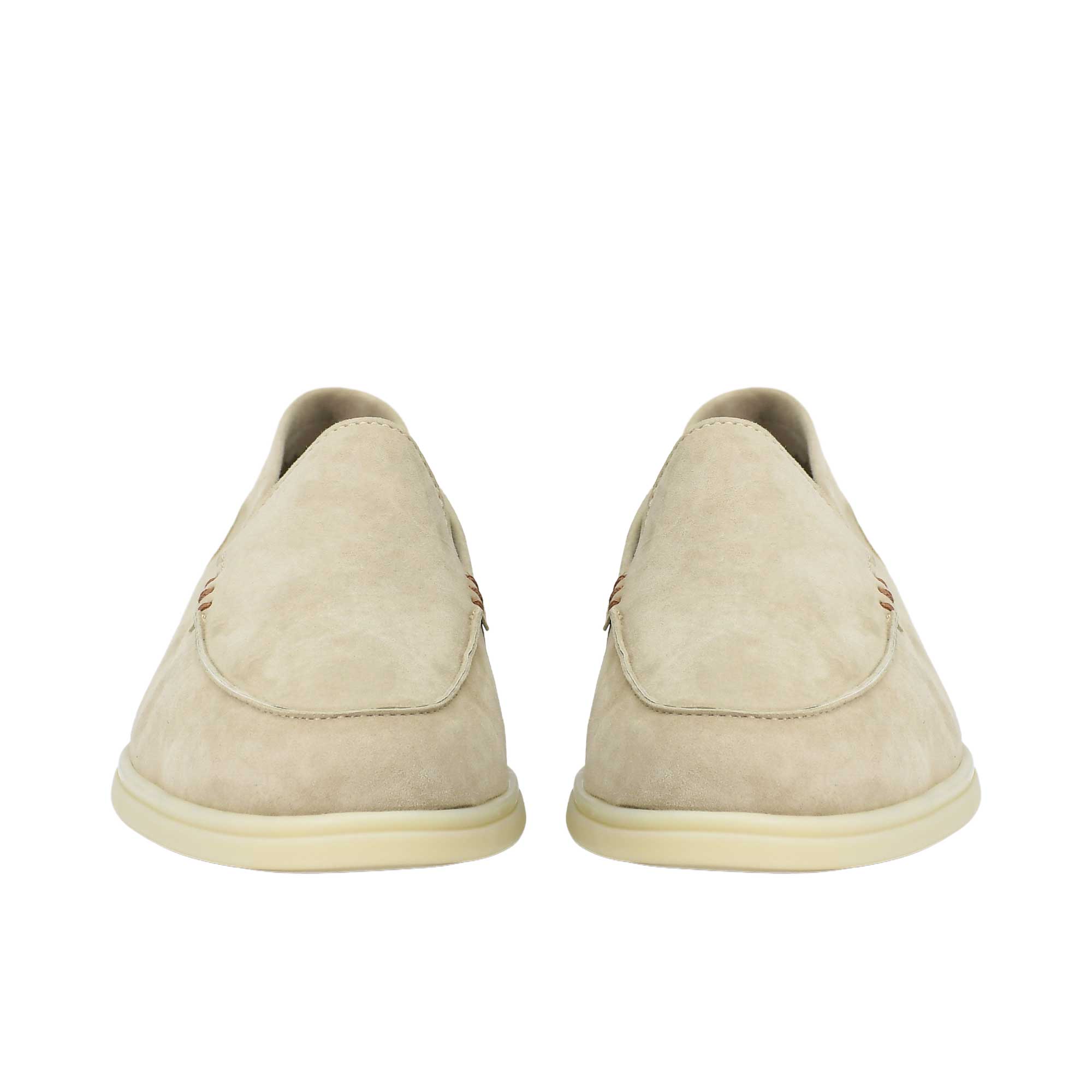 A straight-on, front-facing view of a pair of beige suede slip-on loafers, highlighting their rounded apron toe boxes and clean, symmetrical slip-on design resting on off-white rubber outsoles.