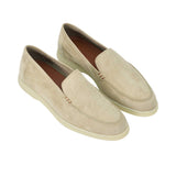 A high-angle, three-quarter perspective of the pair of beige suede loafers. This view highlights the classic apron-toe stitching, the small brown bar-tack style stitch accents at the sides of the tongue, and the contrasting brown leather insoles.