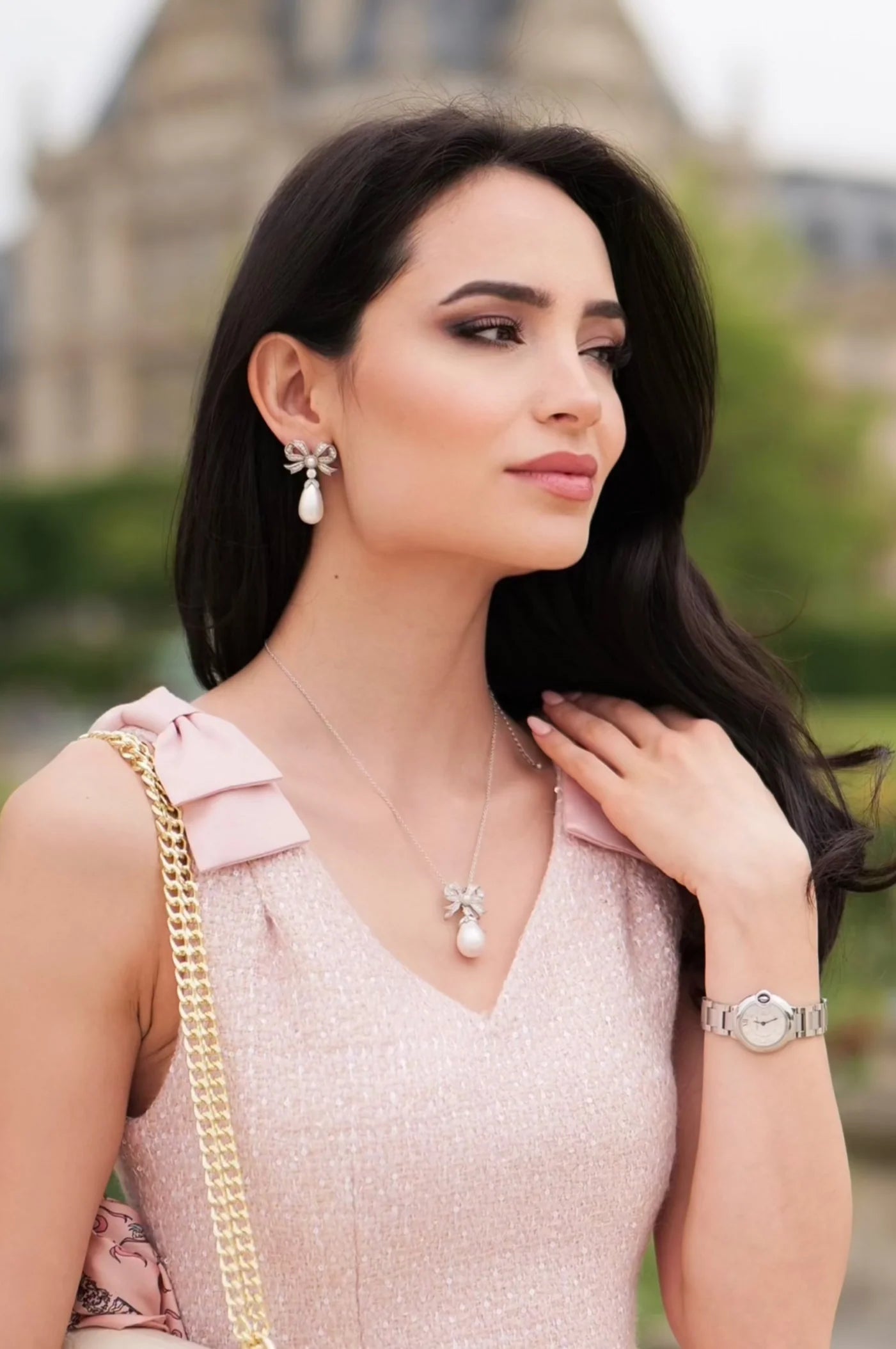 Silver-toned bow-shaped drop earring with clear stones and an elongated off-white pearl.