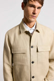 Beige pure linen gabardine overshirt with a pointed collar, dark buttons, and two rectangular chest flap pockets.