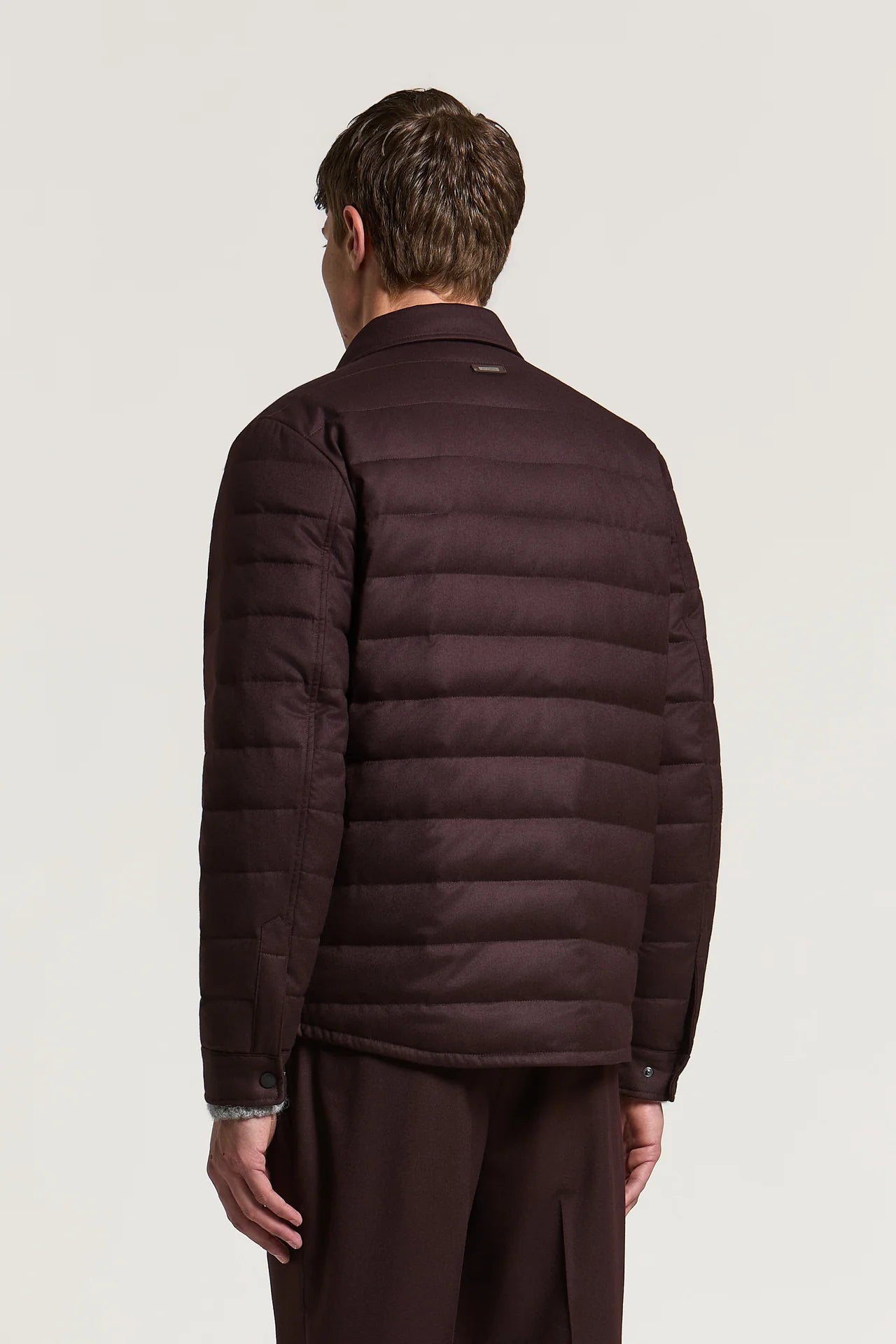 Burgundy red felted jacket with horizontal quilting on the back and sleeves. Features a shirt collar and buttoned cuffs.