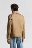 Beige shirt jacket, back view, with a back yoke, long sleeves, buttoned cuffs, and a dark rectangular label below the collar.