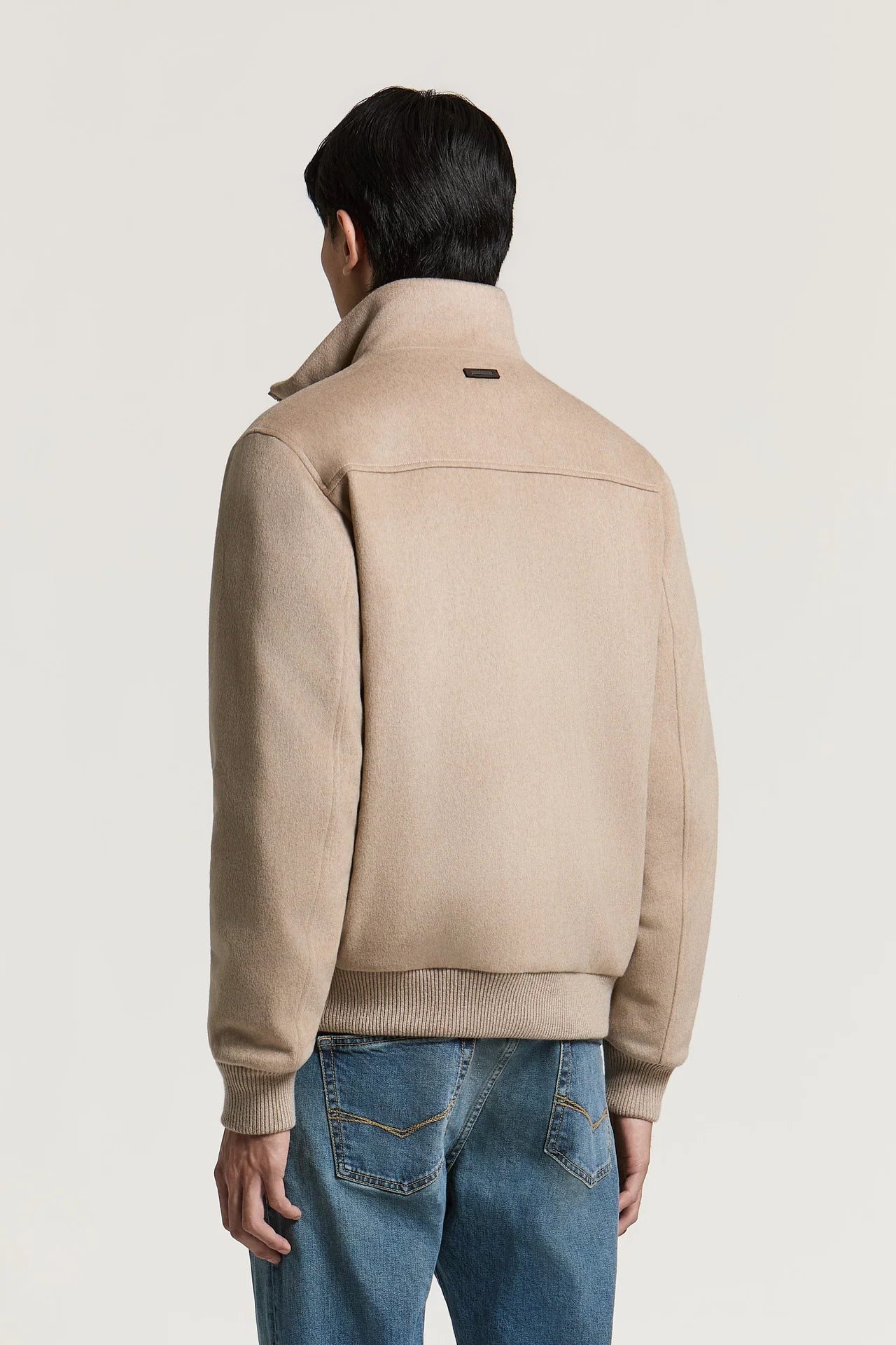 Earth beige bomber jacket with a high stand collar, back yoke seam, and ribbed cuffs and hem. Small dark label on collar.