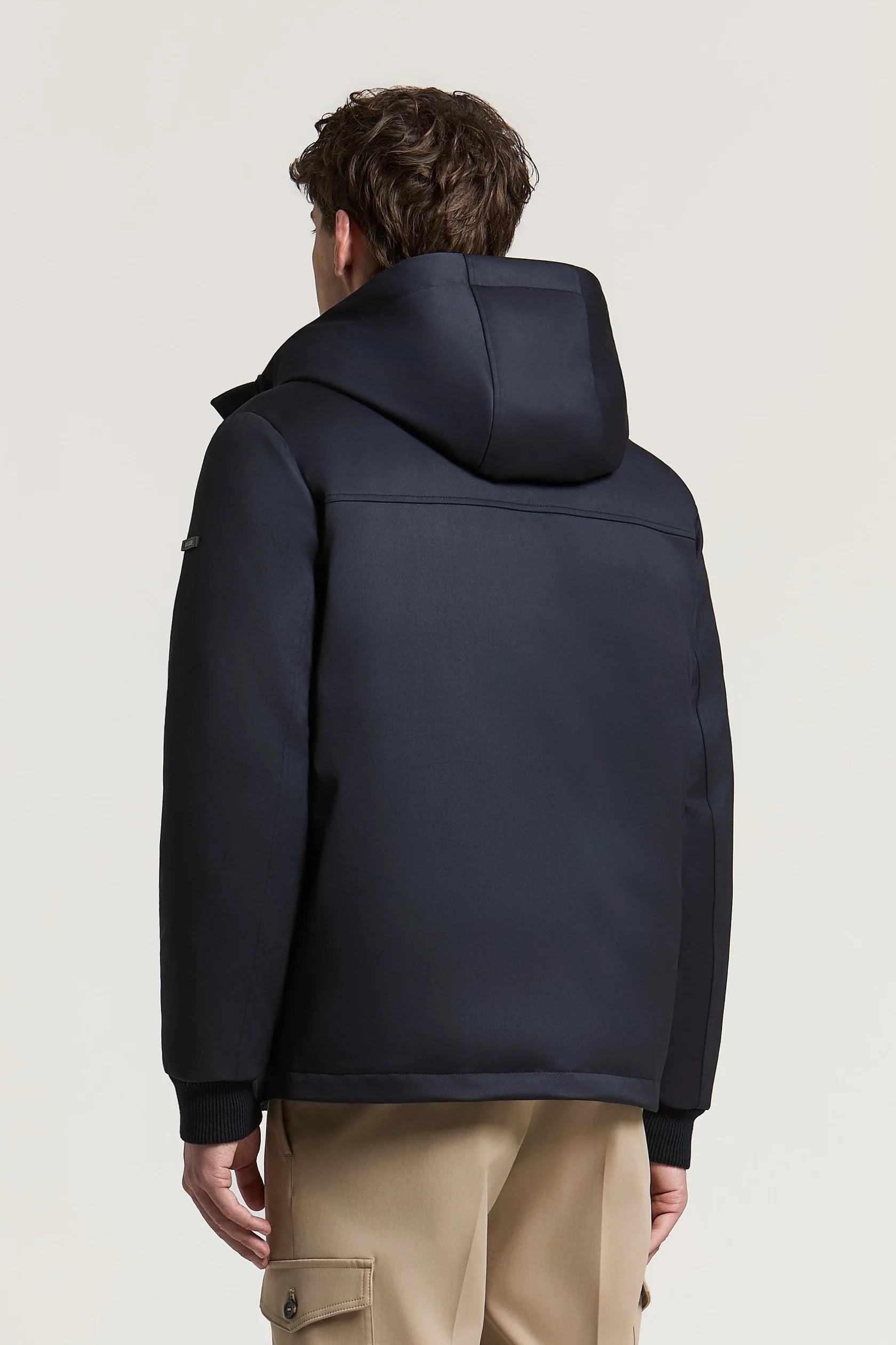Navy blue hooded jacket with smooth fabric, ribbed cuffs and hem, and horizontal stitching on the upper back.