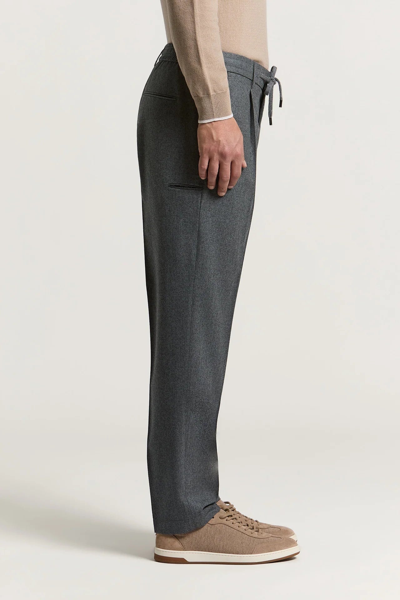 Carbon grey trousers with an elasticated drawstring waist, a back welt pocket, and a side thigh welt pocket.