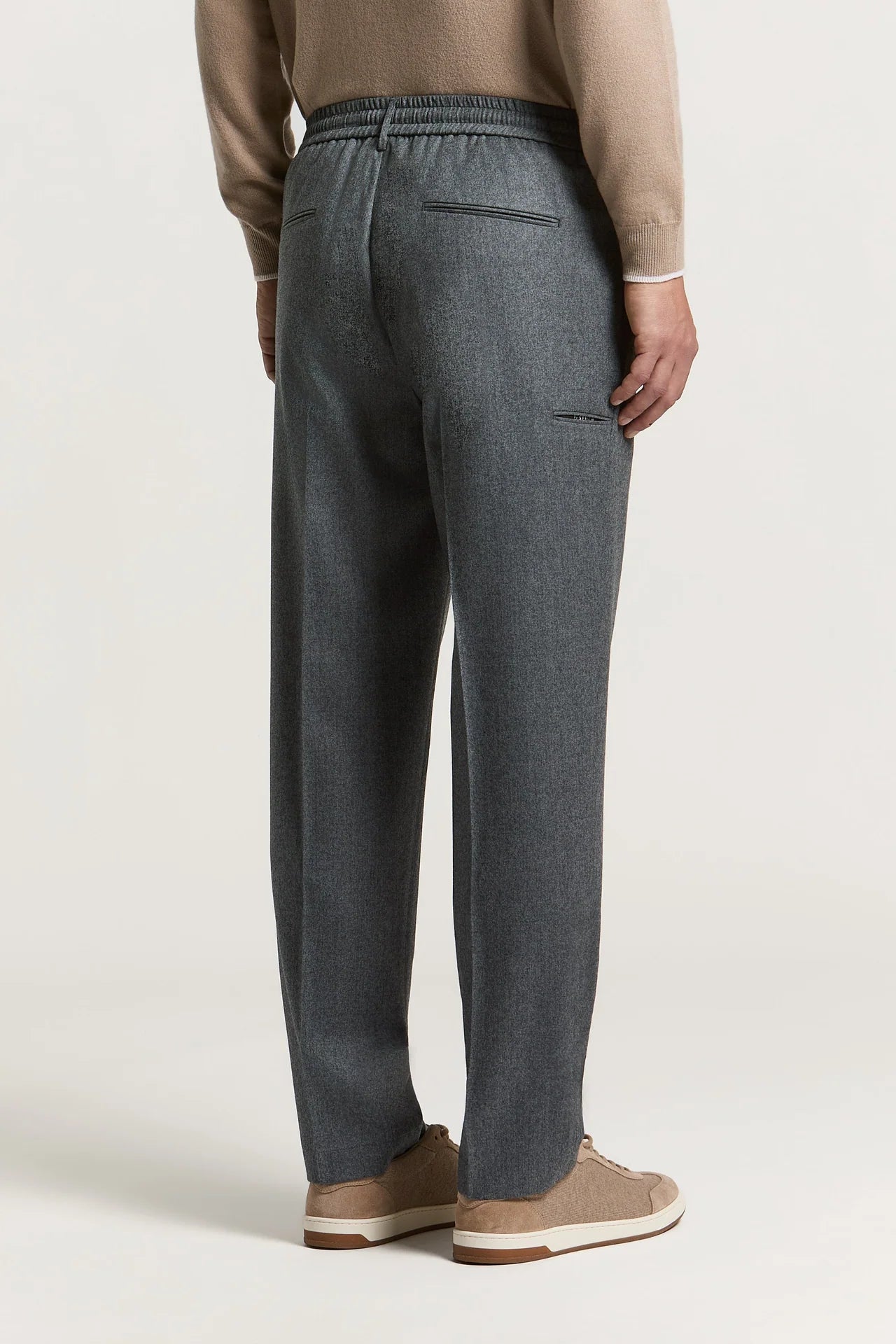 Carbon grey trousers with an elasticated waistband, two rear welt pockets, and a small zippered pocket on the right thigh.