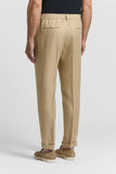 Beige pure linen gabardine trousers with an elasticated back waistband, two back welt pockets, and cuffed hems.