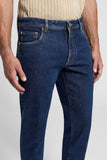 Dark blue slim fit cotton twill jeans with contrast tan stitching, silver-toned button, zipper fly, and five-pocket design.