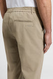 Beige cotton poplin jogger trousers featuring an elasticated waist, belt loops, and two back welt pockets, one with a fabric