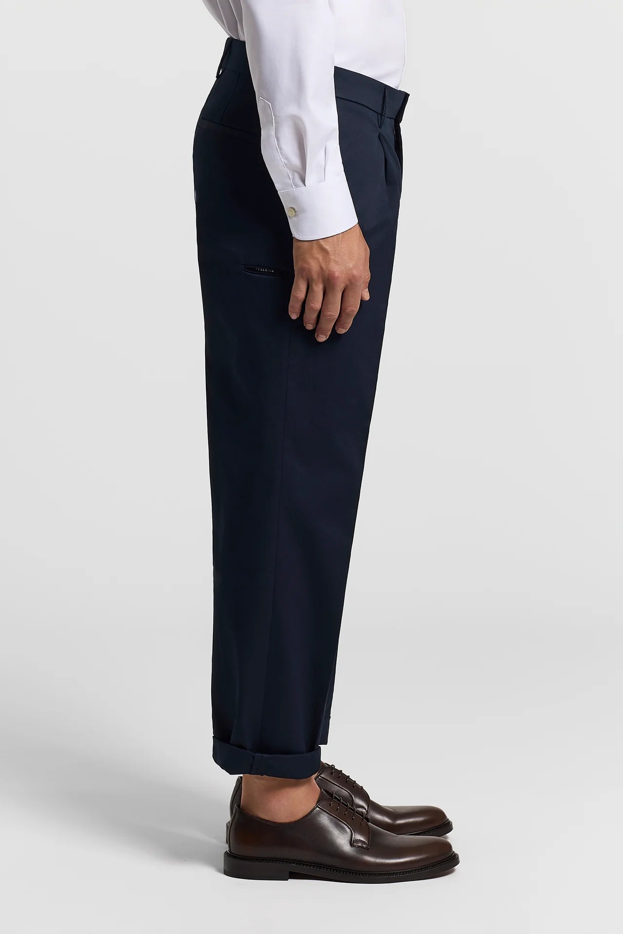 Dark blue pure cotton gabardine trousers with darts, side pockets, one with a zipper, and cuffed hems.