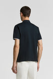 Dark blue piquet polo shirt with short sleeves. The collar and sleeve cuffs feature a thin white stripe.