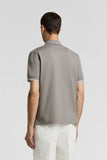 Grey piquet polo shirt, back view, with short sleeves and white-trimmed cuffs.