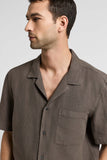 Brown linen canvas camp shirt with short sleeves, an open collar, a button-front closure, and a single chest patch pocket.