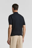 Dark blue short-sleeved knitted polo shirt with a ribbed collar, prominent vertical ribbed texture, and ribbed cuffs and hem.