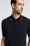 Navy knitted cotton polo shirt with a beige-trimmed collar, a two-button placket, and short sleeves.