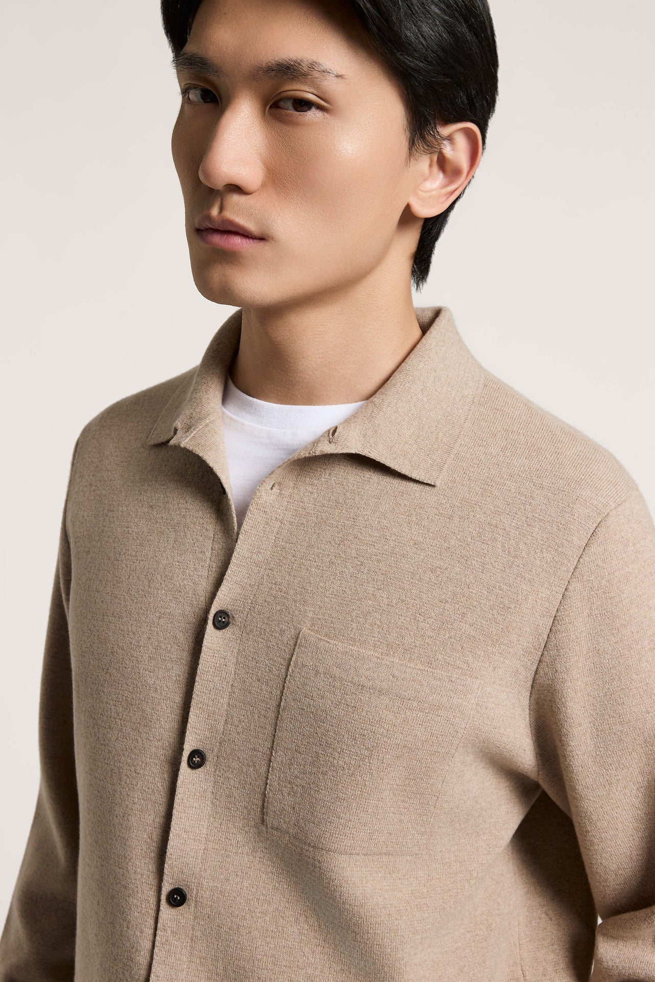 Earth beige knit sweater with a spread collar, full button-front closure with dark buttons, and a left chest patch pocket.