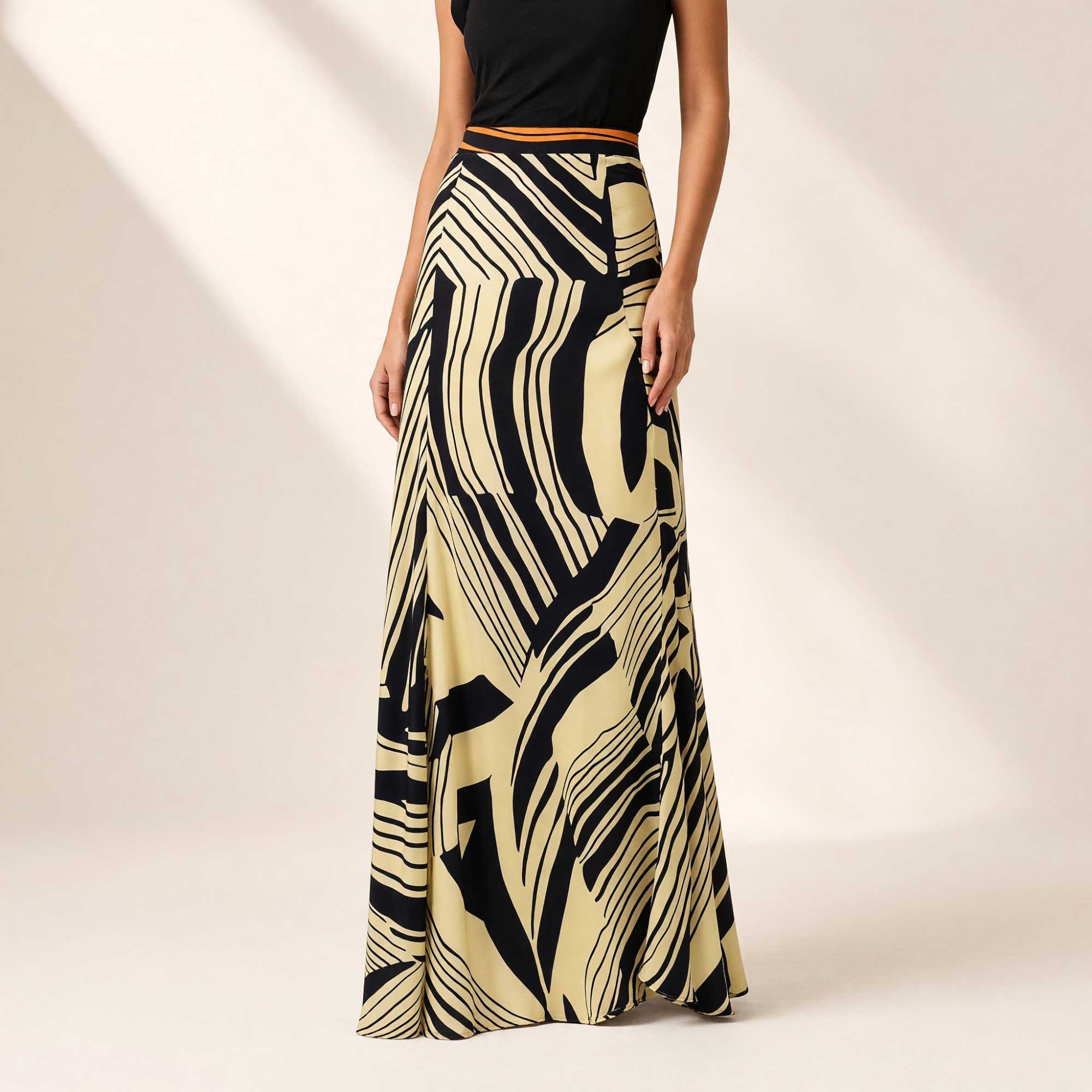 Ivory maxi skirt with an abstract black stripe pattern and a thin tangerine waistband.
