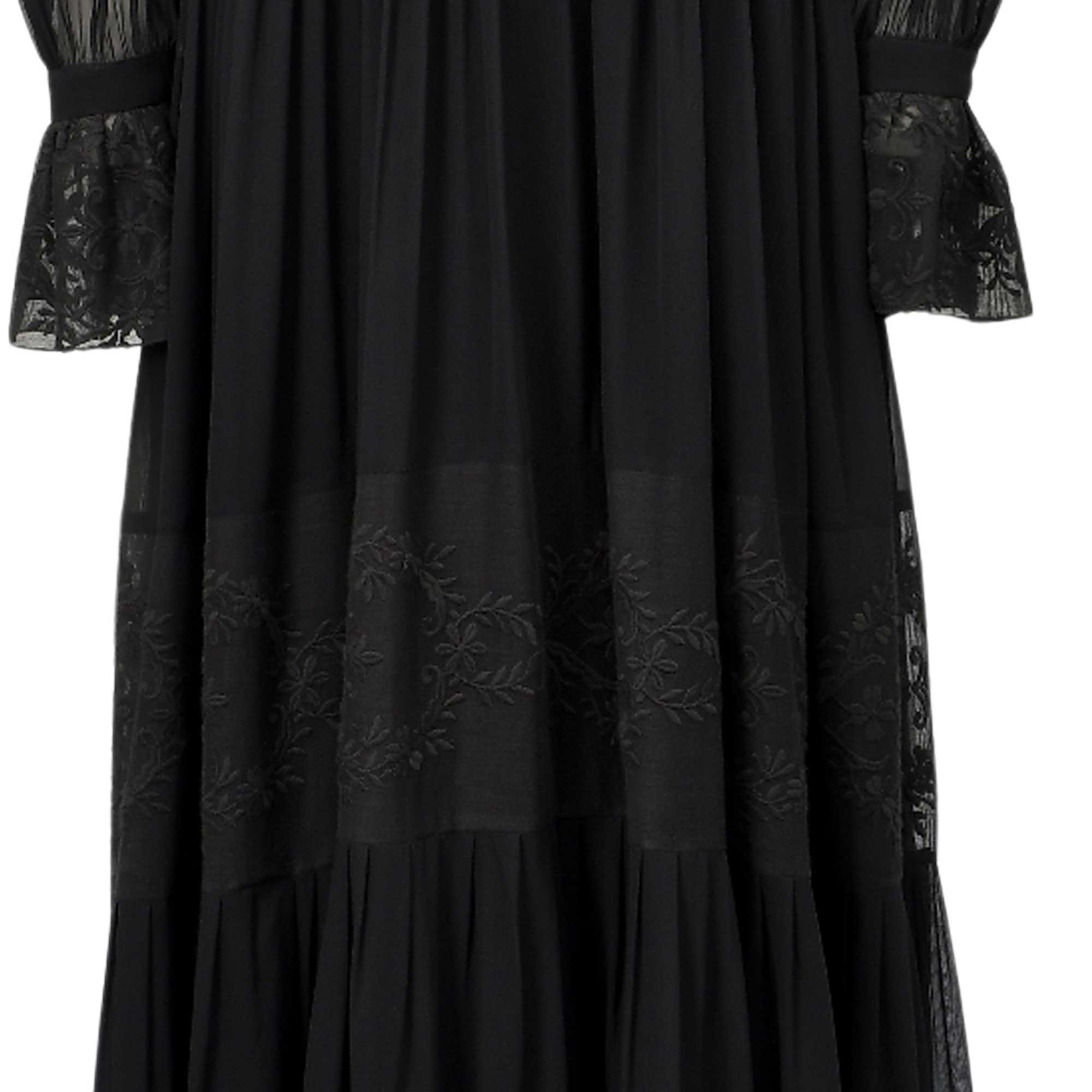 Black sheer dress with elbow-length sleeves featuring lace cuffs. The skirt has an embroidered floral band and a pleated lowe