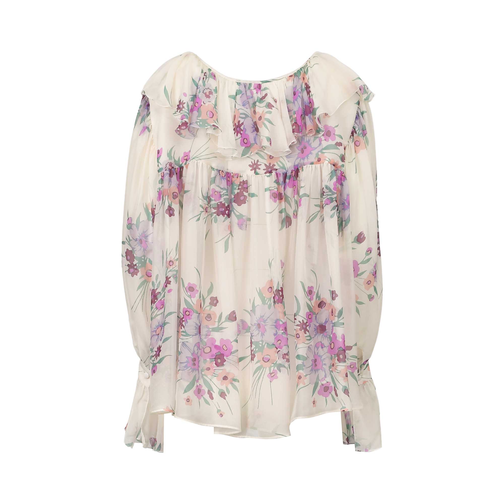 Cream floral blouse with lilac, purple, pink, and green flowers. Features a ruffled neckline, gathered bodice, and ruffled cu