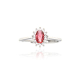 Silver-toned ring featuring an oval-cut ruby-red central stone surrounded by a cluster of small clear stones.