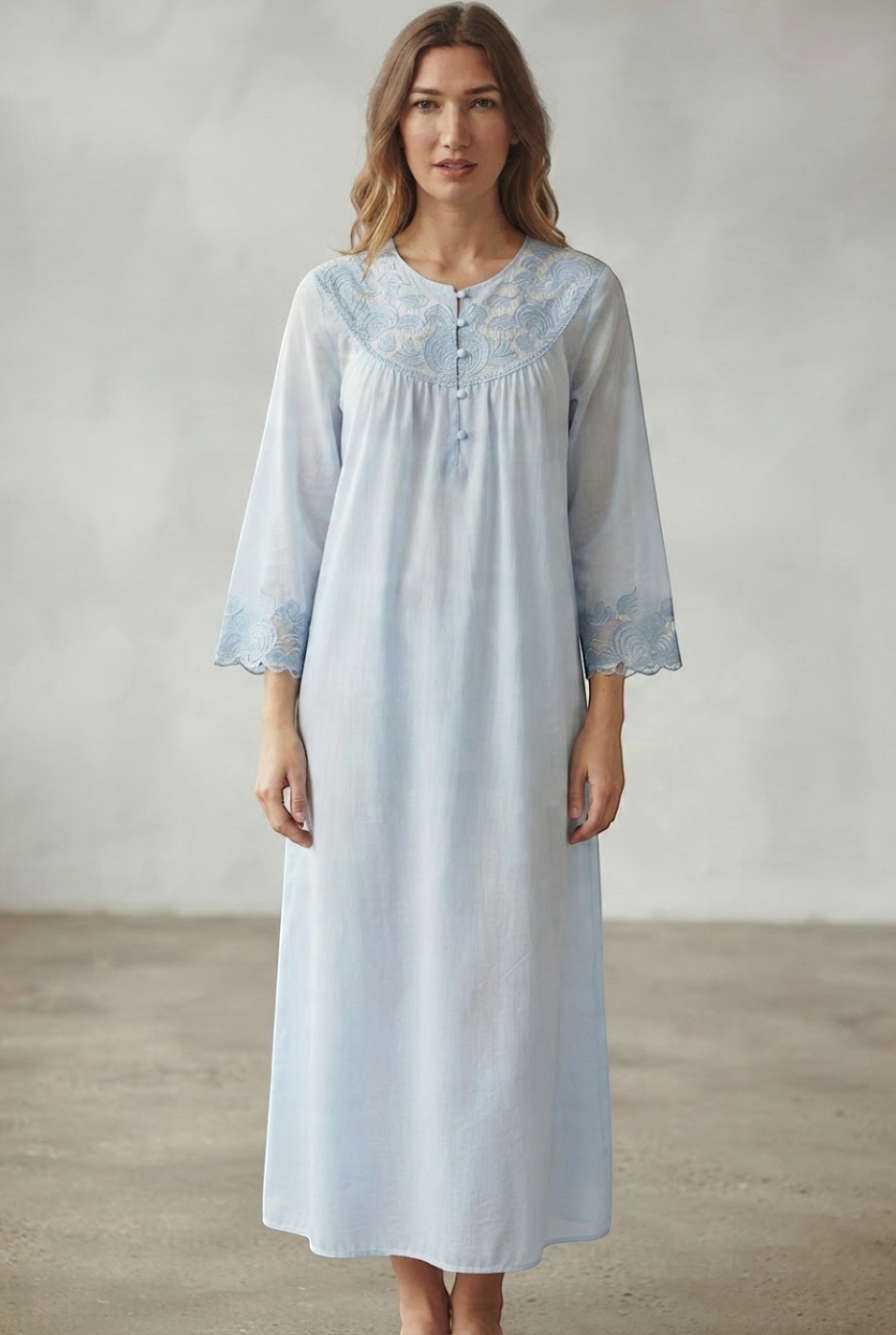 Light blue cotton abaya with round neck, gathered yoke, three front buttons, and light blue floral embroidery on the yoke and