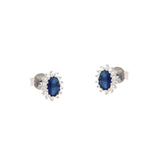 Pair of silver-toned stud earrings, each with an oval dark blue stone surrounded by a halo of small clear stones.