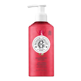 A 250ml reddish-pink translucent pump bottle of Roger & Gallet Gingembre Rouge Wellbeing Body Lotion, featuring a white pump dispenser and a central round logo.