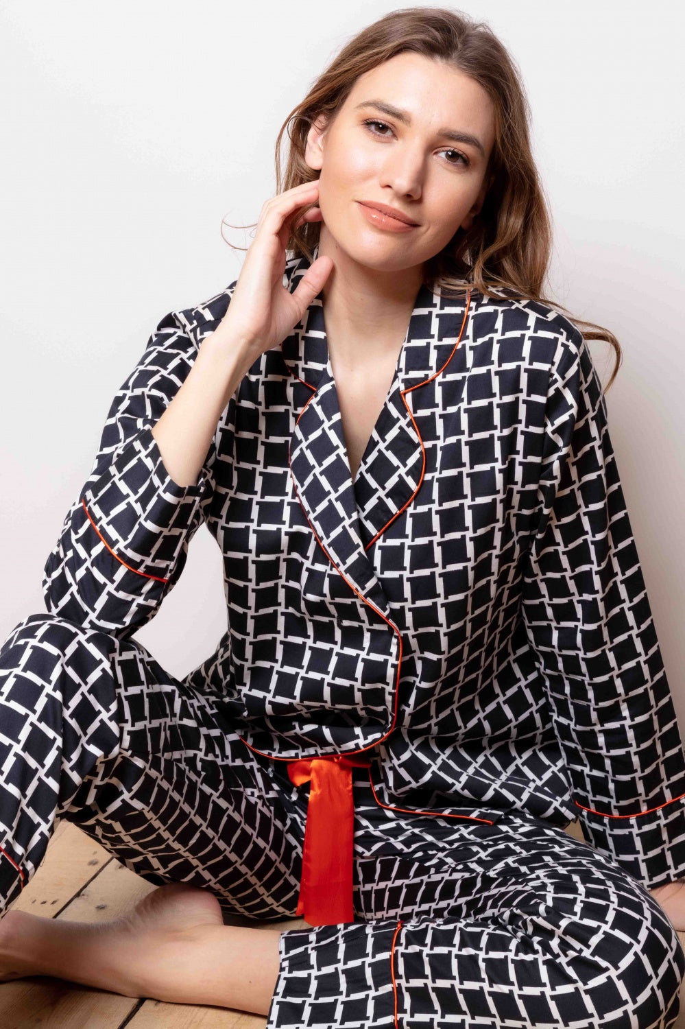 Midnight blue cotton sateen pajama set with white retro cube pattern, revere collar, orange piping, and orange waist tie.