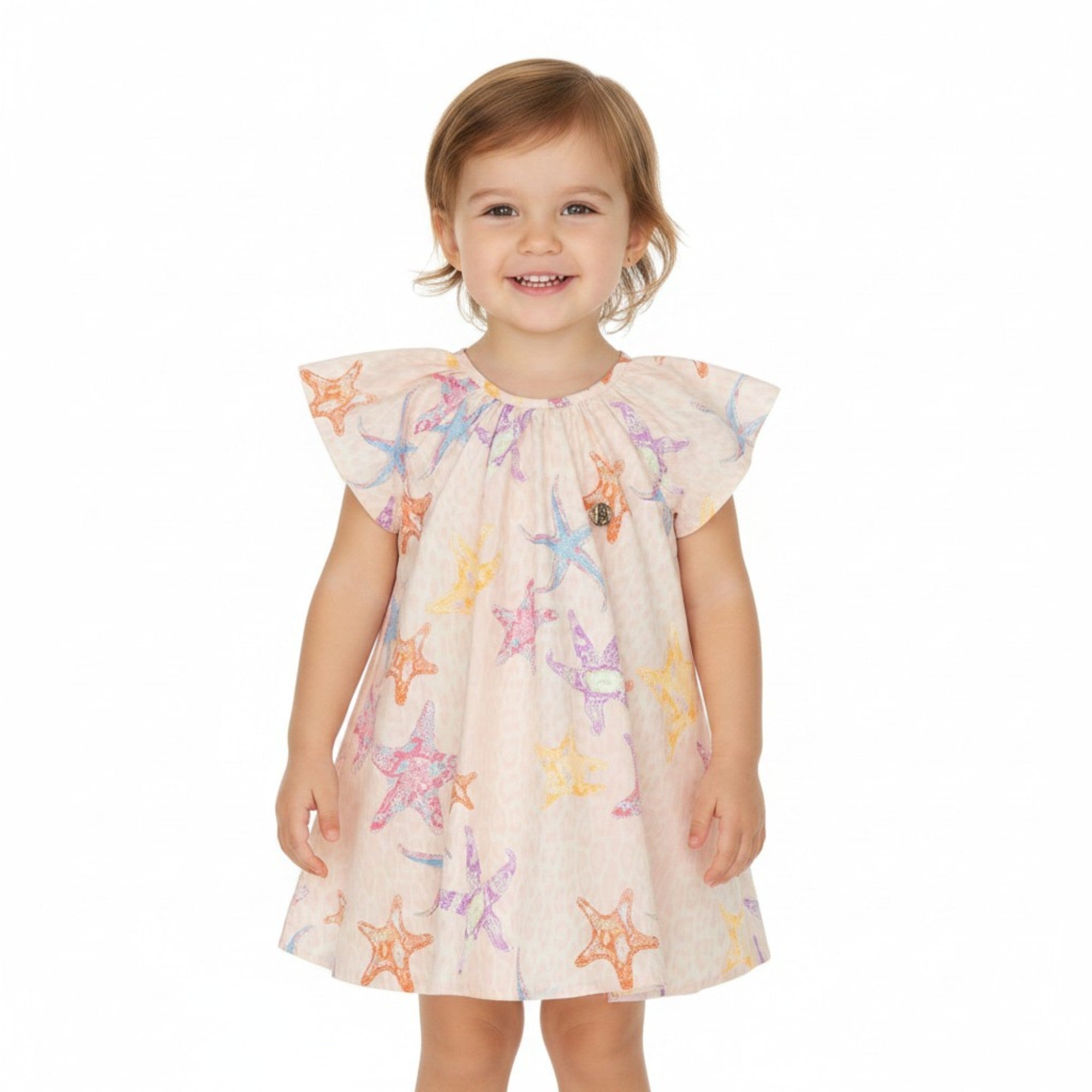 Front view of a smiling toddler girl modeling the lightweight Roberto Cavalli pink starfish and leopard print dress with flutter sleeves against a clean white background.