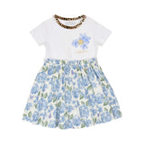 Front view of a Roberto Cavalli girl's white t-shirt dress featuring a leopard-print collar, blue hydrangea chest graphics with a gold RC monogram, and a gathered blue floral skirt, available at BLUE SALON.