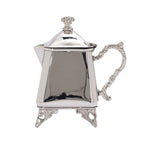 A silver-plated cream pitcher with an ornate scroll handle and a pyramidal lid with a decorative finial.