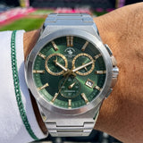 Silver-toned watch with dark green sunburst dial, gold-toned markers/hands, three sub-dials, and a date window, on a silver-t